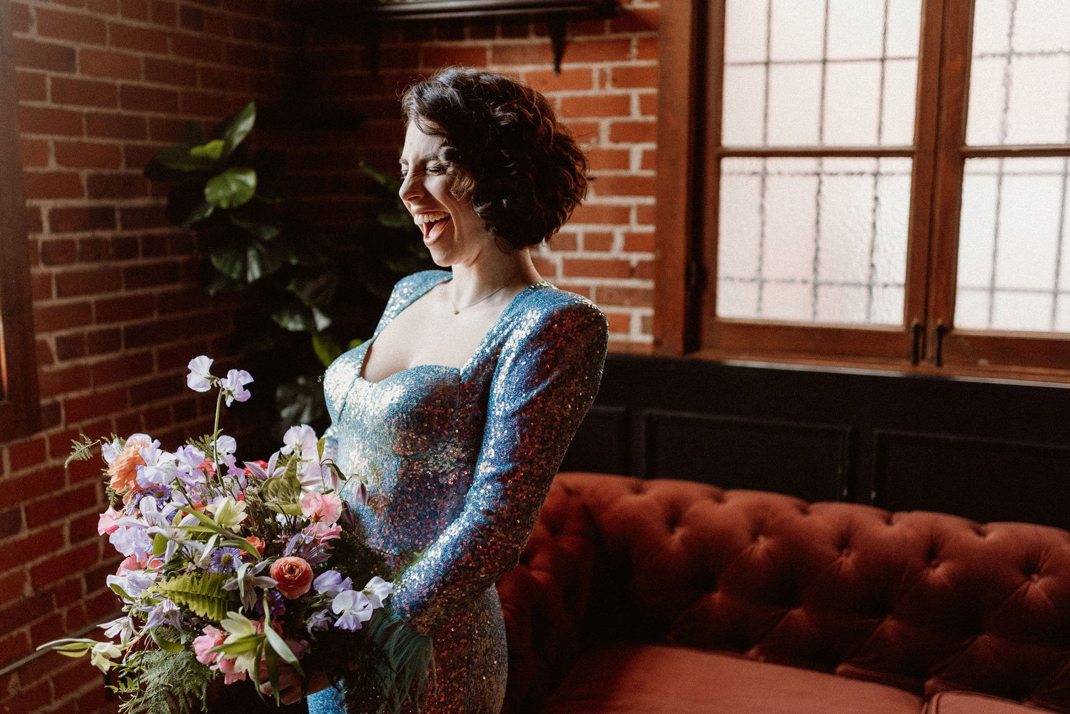 Bride in a sequin jumpsuit holding a bold, colorful bouquet