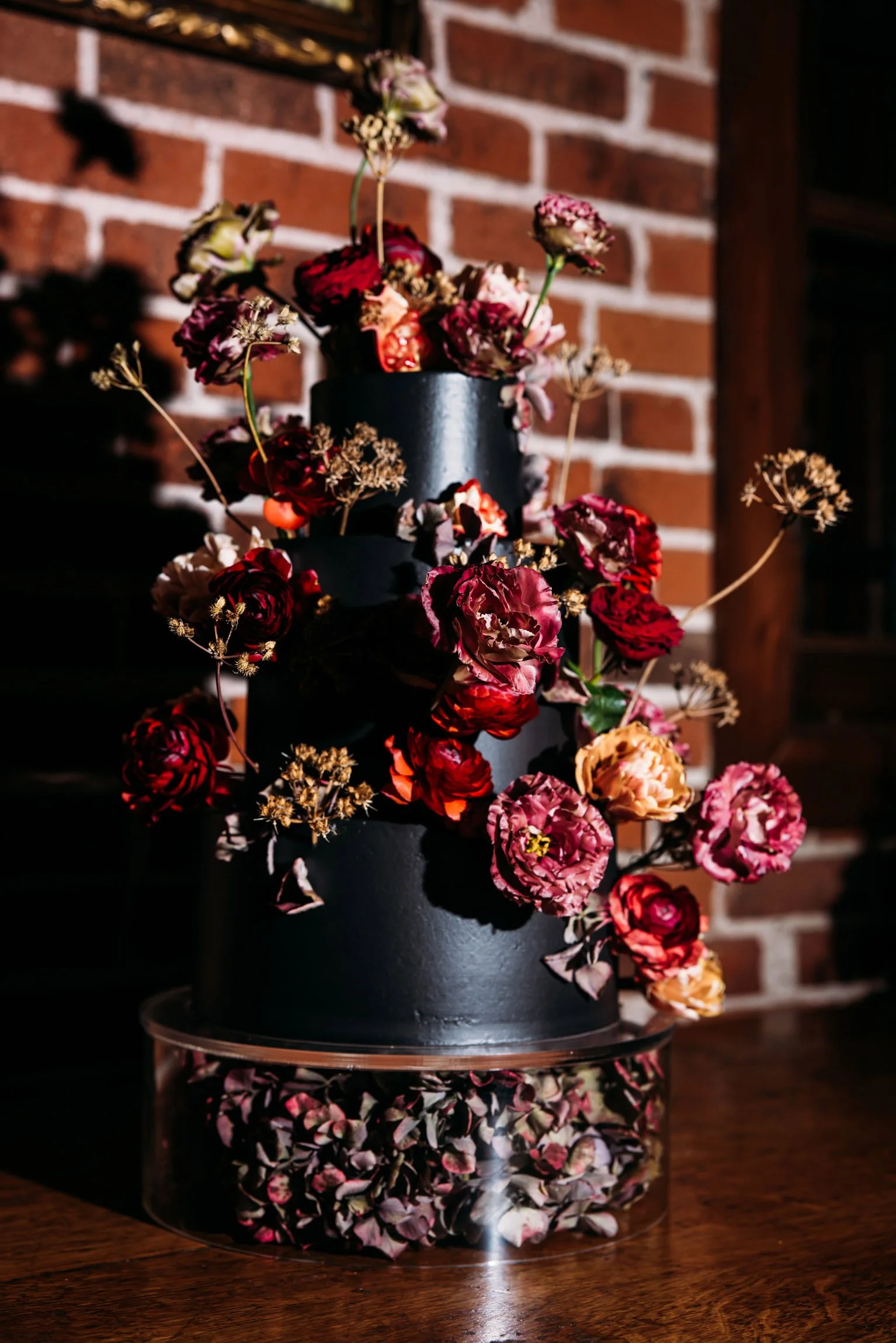 Black wedding cake adorned with dramatic dark florals