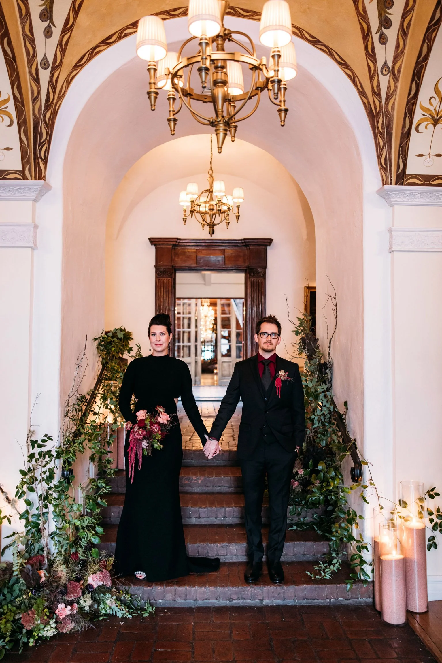 Couple amidst greenery, blooms, and candlelight
